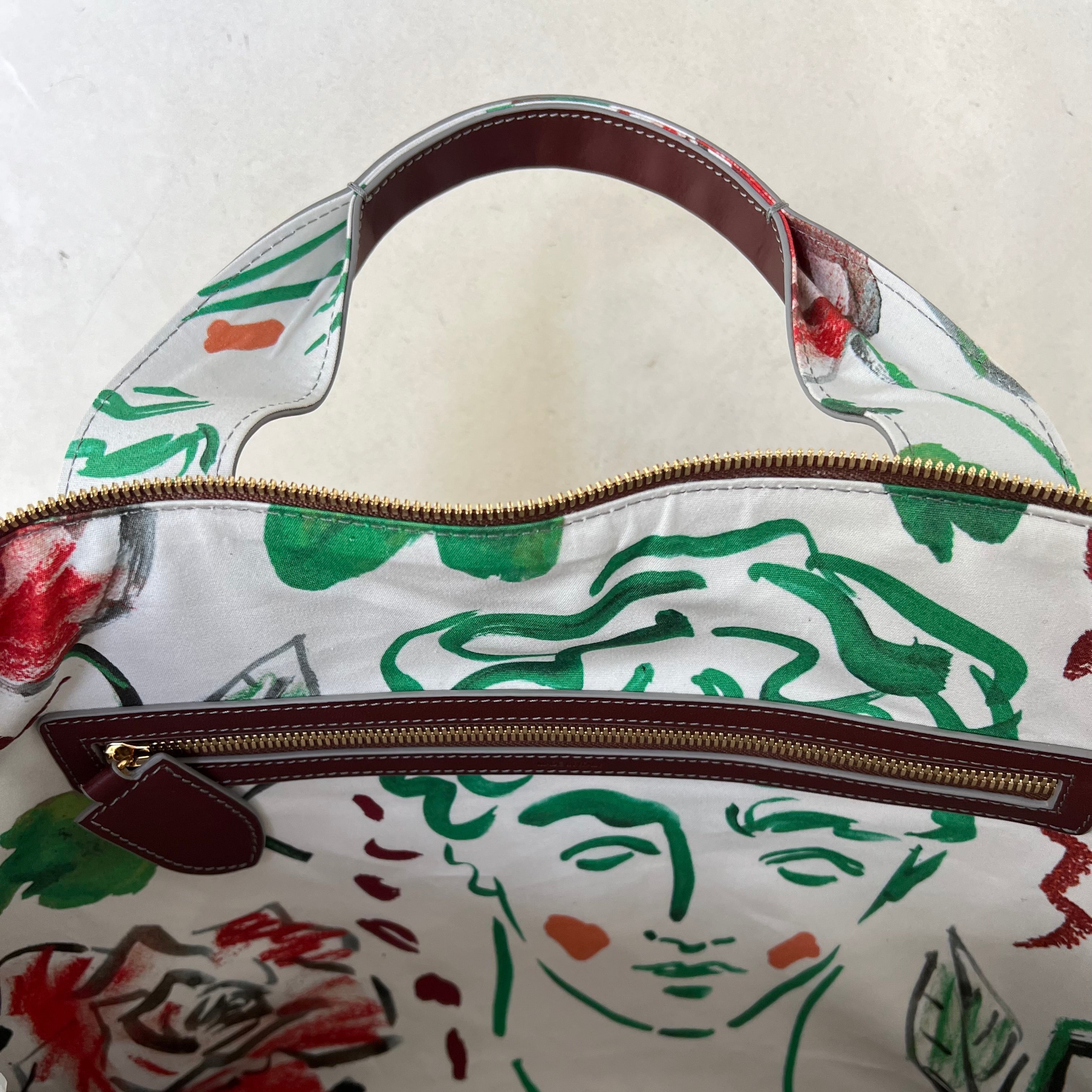 Handbag with artistic design of a face and flowers on a white background